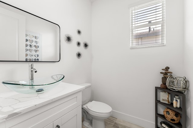 bathroom featuring wood finished floors, vanity, toilet, and baseboards