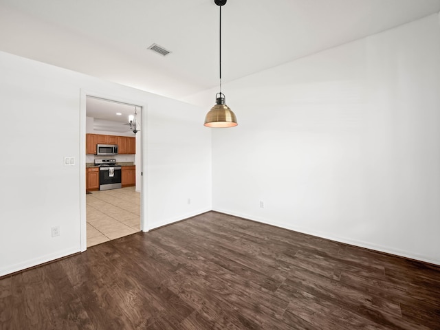 unfurnished dining area featuring wood finished floors, visible vents, and baseboards