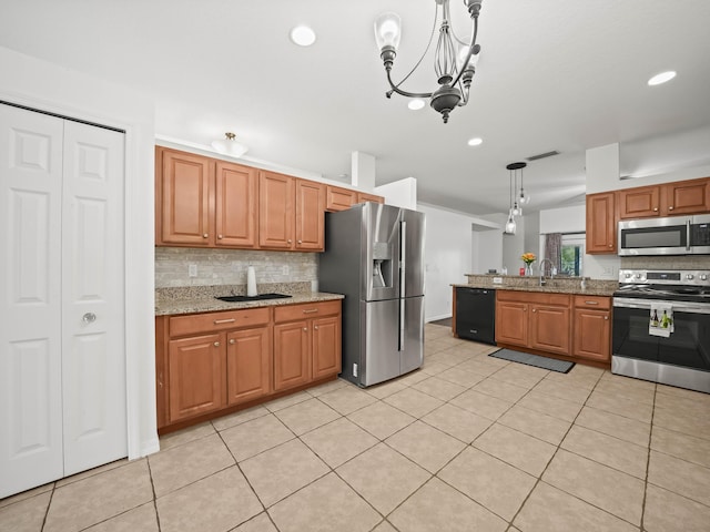 kitchen with light stone counters, stainless steel appliances, a sink, backsplash, and decorative light fixtures