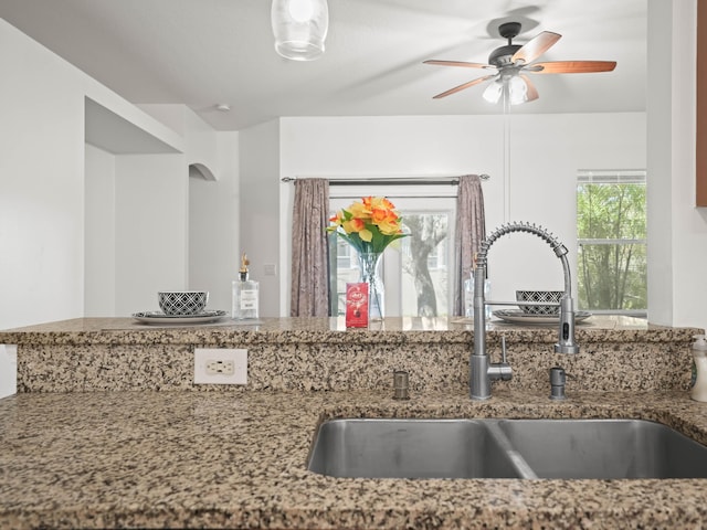 kitchen featuring stone counters, a ceiling fan, and a sink