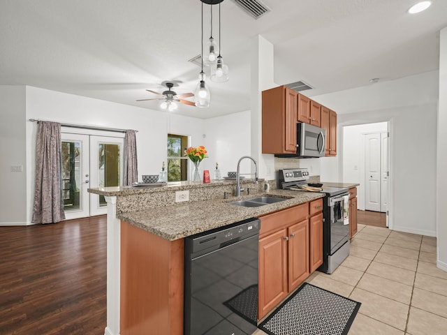 kitchen with appliances with stainless steel finishes, visible vents, a sink, and light stone countertops