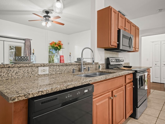 kitchen featuring light stone countertops, stainless steel appliances, a sink, and light tile patterned flooring