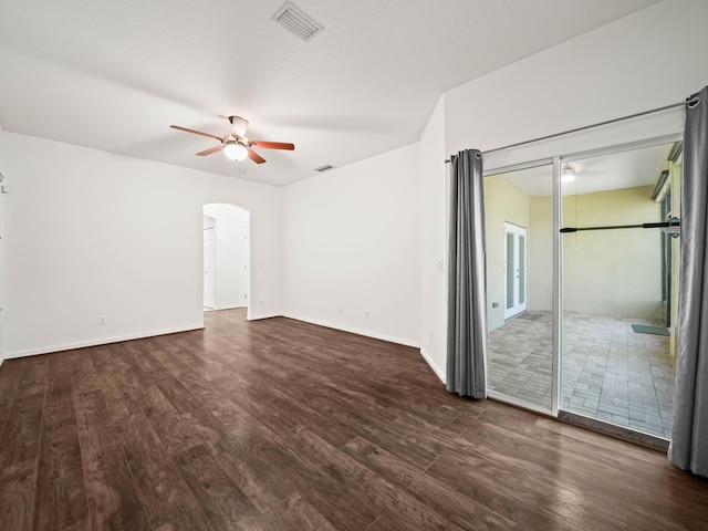 spare room featuring visible vents, arched walkways, a ceiling fan, baseboards, and wood finished floors