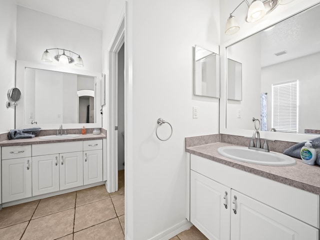 full bathroom with tile patterned flooring, visible vents, two vanities, and a sink