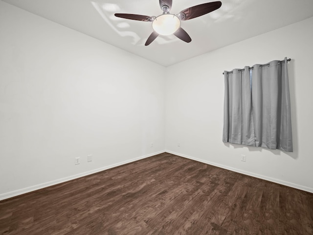 empty room featuring dark wood-type flooring, baseboards, and a ceiling fan