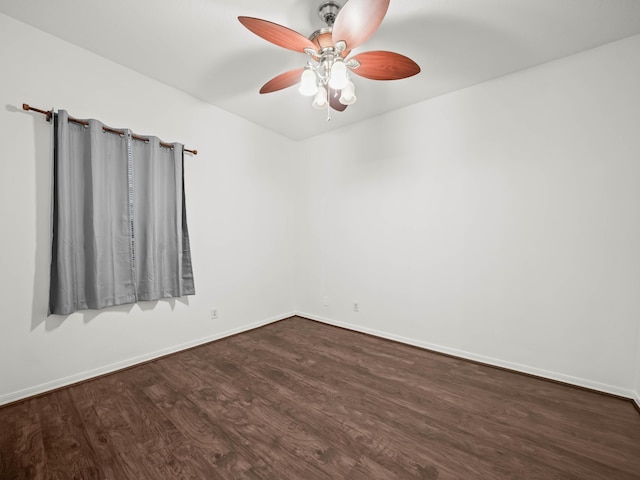 spare room featuring ceiling fan, dark wood-style flooring, and baseboards