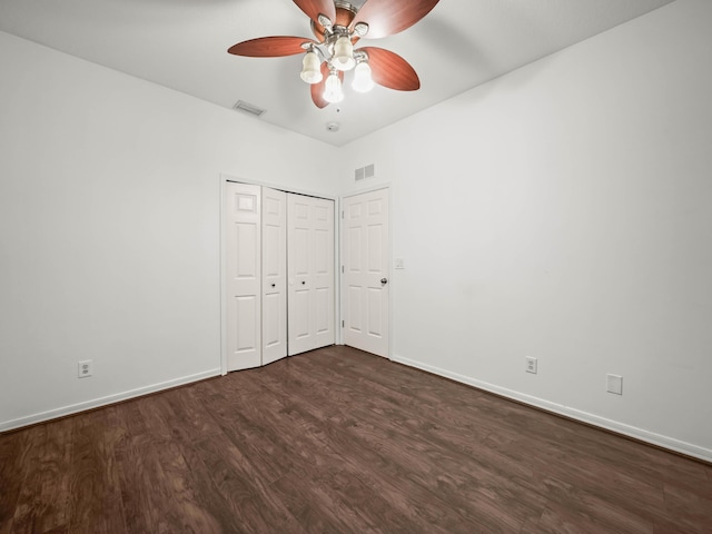 unfurnished bedroom featuring dark wood-type flooring, a closet, visible vents, and baseboards