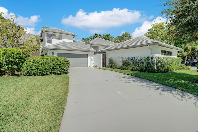 prairie-style home with a garage, stucco siding, driveway, and a front yard