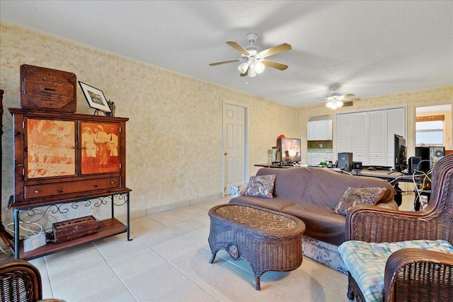 living area featuring a textured ceiling, wallpapered walls, light tile patterned flooring, and baseboards