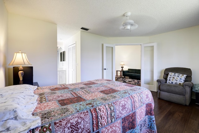 bedroom with visible vents, a textured ceiling, and wood finished floors