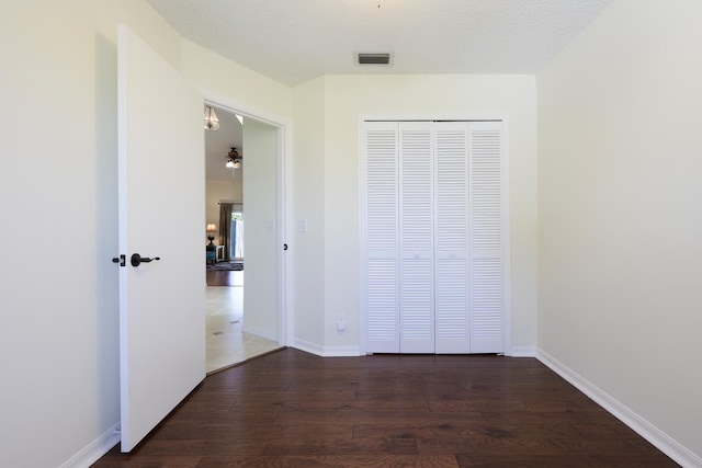 unfurnished bedroom featuring a closet, visible vents, baseboards, and wood finished floors