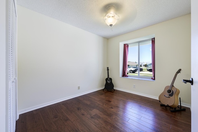 spare room with baseboards, dark wood finished floors, and a textured ceiling