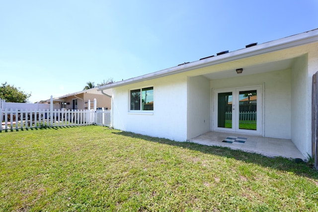 rear view of house with a yard, a patio area, fence, and stucco siding