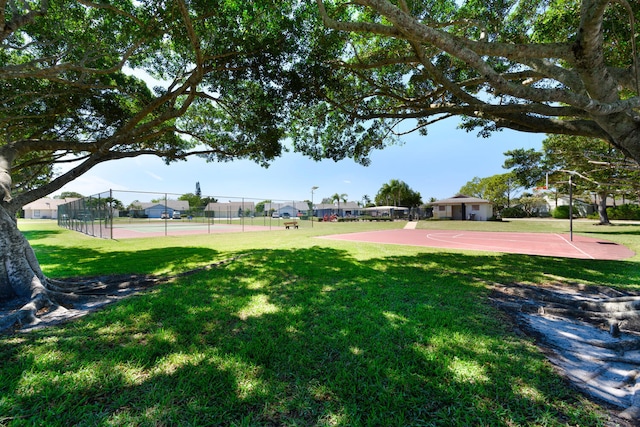 view of yard featuring a tennis court, community basketball court, and fence