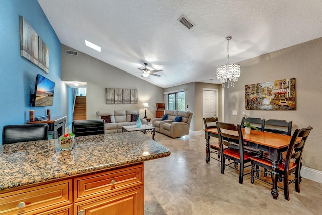 interior space featuring a textured ceiling, baseboards, visible vents, ceiling fan with notable chandelier, and vaulted ceiling