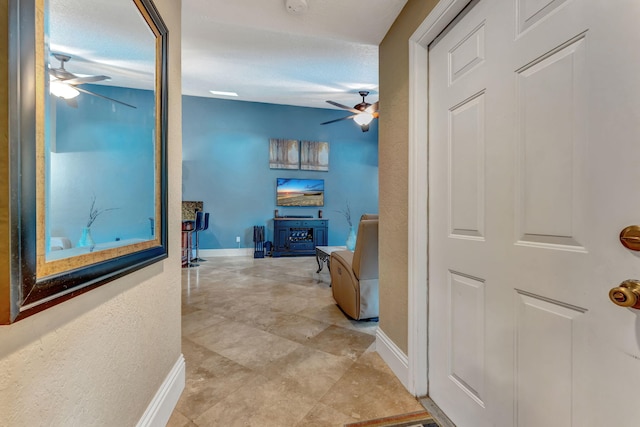 hall with a textured wall and baseboards