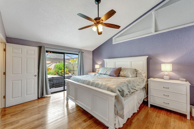 bedroom featuring light wood finished floors, ceiling fan, access to exterior, vaulted ceiling, and a textured ceiling