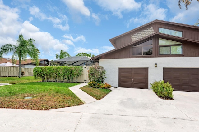 view of side of home with concrete driveway, glass enclosure, an attached garage, fence, and a yard