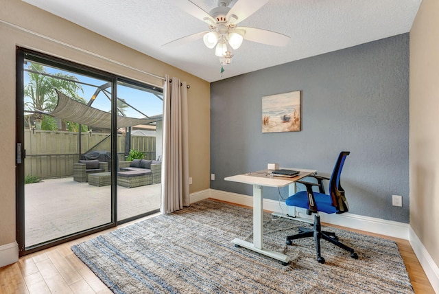 office space with a textured ceiling, baseboards, wood finished floors, and a ceiling fan