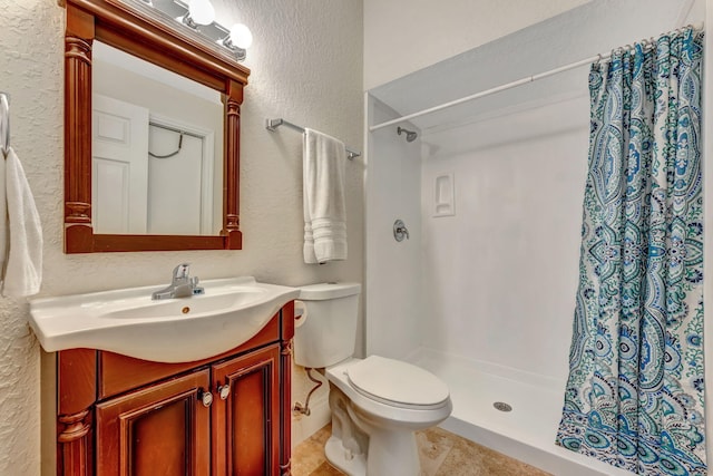 bathroom with a textured wall, a stall shower, vanity, and toilet