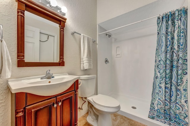 bathroom featuring toilet, vanity, tile patterned floors, a textured wall, and a shower stall