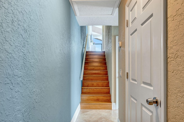 stairway with a textured wall and baseboards