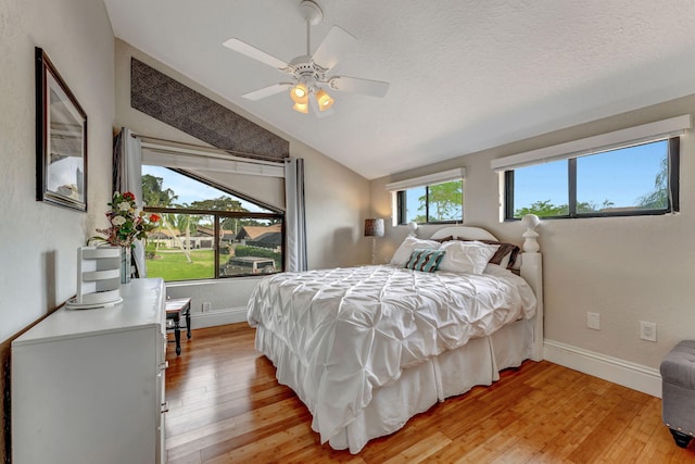 bedroom featuring light wood-style flooring, baseboards, vaulted ceiling, and a textured ceiling