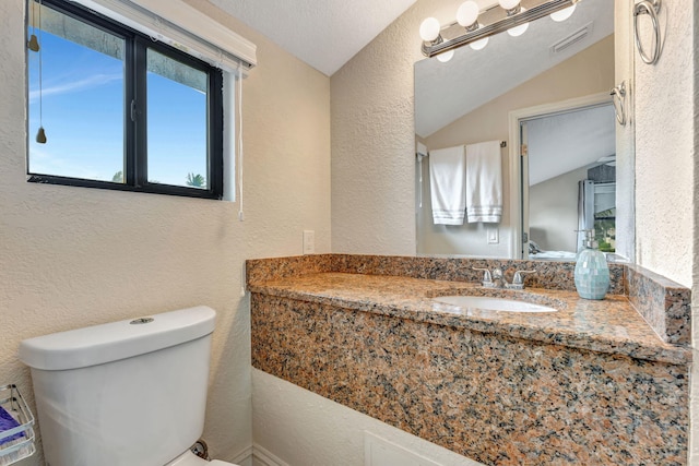half bathroom featuring toilet, visible vents, lofted ceiling, and a textured wall