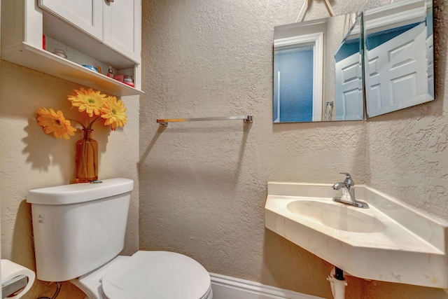 half bathroom with toilet and a textured wall