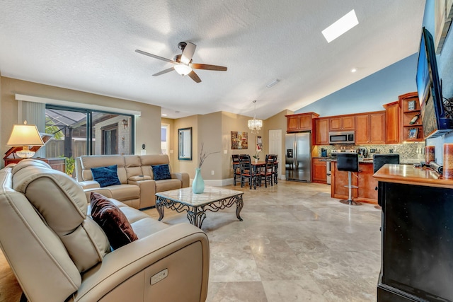 living area with lofted ceiling with skylight, a textured ceiling, baseboards, and a ceiling fan