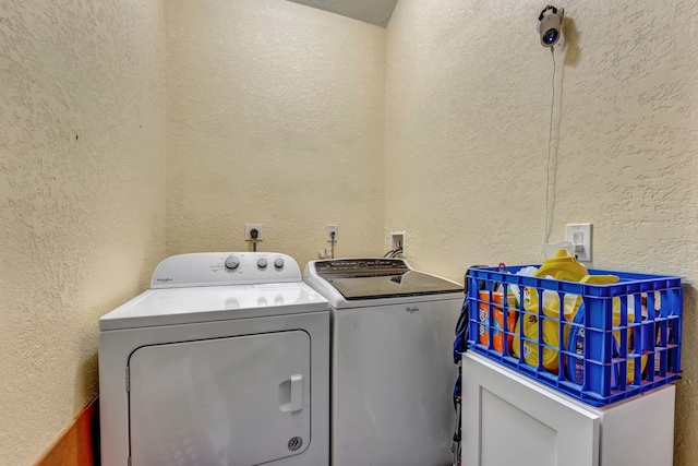 clothes washing area featuring a textured wall, laundry area, and washer and clothes dryer