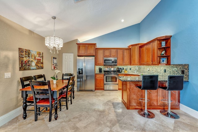 kitchen featuring appliances with stainless steel finishes, dark stone counters, brown cabinets, and a peninsula