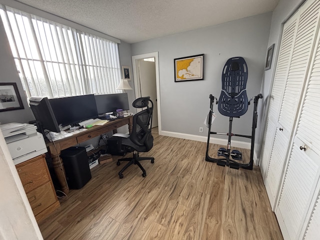 home office featuring baseboards, light wood-style flooring, and a textured ceiling