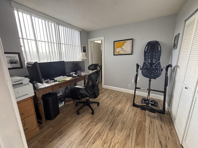 office space featuring a textured ceiling, baseboards, and wood finished floors