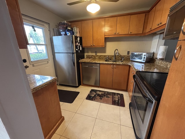 kitchen featuring a toaster, decorative backsplash, brown cabinetry, appliances with stainless steel finishes, and a sink