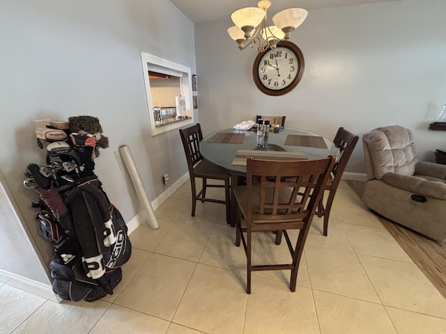 dining space featuring light tile patterned floors, baseboards, and an inviting chandelier