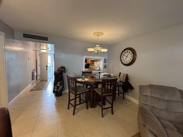 dining room featuring light tile patterned floors, visible vents, a textured ceiling, a chandelier, and baseboards