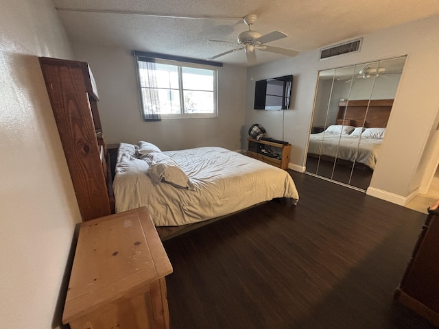 bedroom with a textured ceiling, wood finished floors, visible vents, baseboards, and a closet