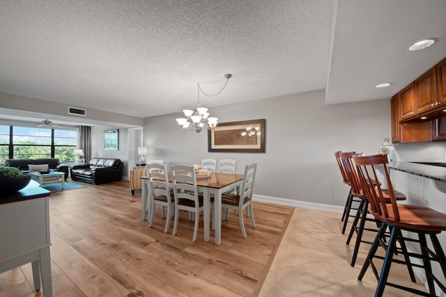 dining room with visible vents, baseboards, a textured ceiling, and light wood-style flooring