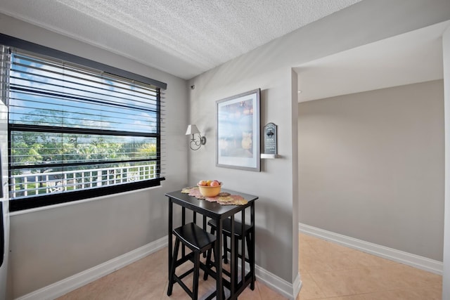 dining room with tile patterned floors, baseboards, and a textured ceiling