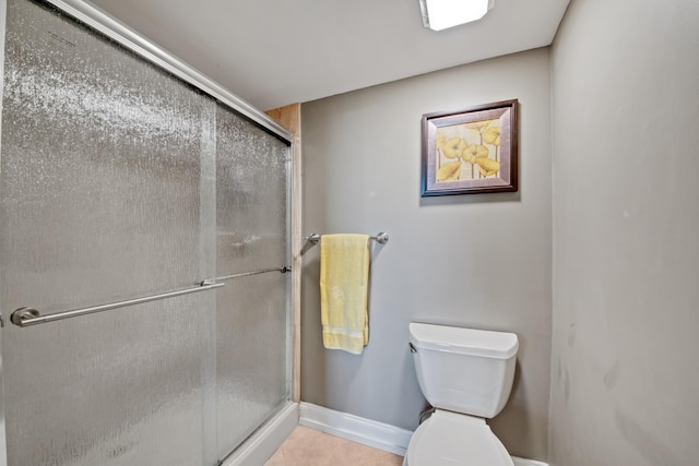 bathroom with tile patterned flooring, toilet, baseboards, and a stall shower