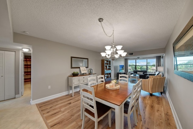 dining room featuring a notable chandelier, visible vents, light wood-type flooring, and baseboards