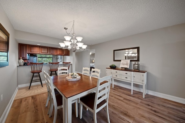 dining area featuring an inviting chandelier, plenty of natural light, light wood-style floors, and baseboards