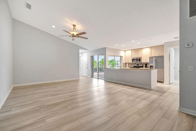 unfurnished living room with a ceiling fan, visible vents, light wood-style flooring, and baseboards