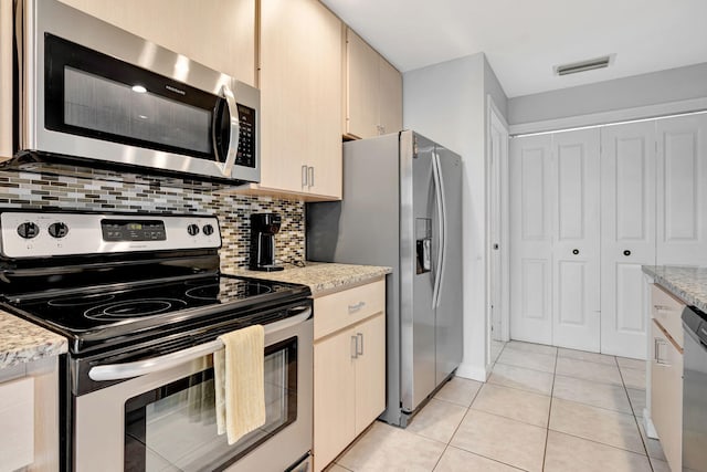 kitchen featuring light tile patterned floors, visible vents, appliances with stainless steel finishes, light stone countertops, and tasteful backsplash