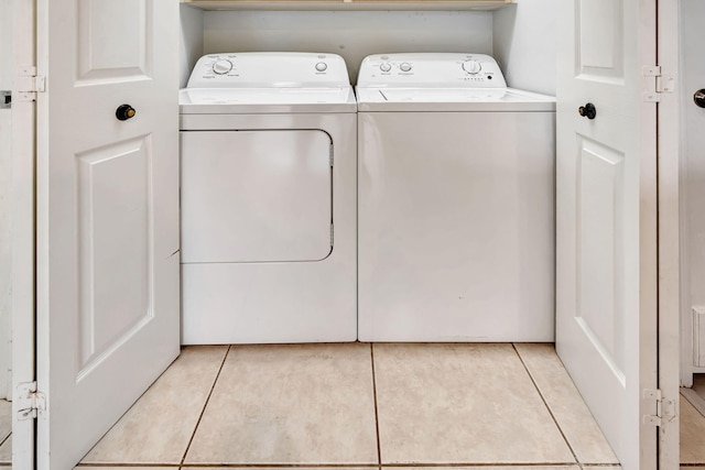 clothes washing area with laundry area, separate washer and dryer, and light tile patterned flooring