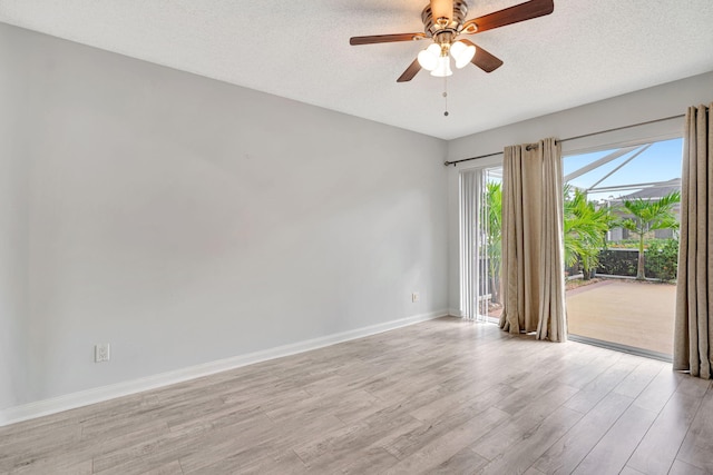 empty room with a textured ceiling, ceiling fan, light wood finished floors, and baseboards