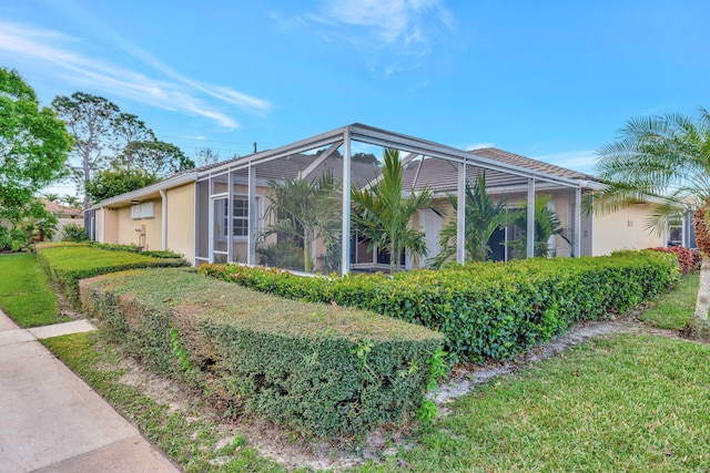 view of side of home with a lanai, a lawn, and stucco siding