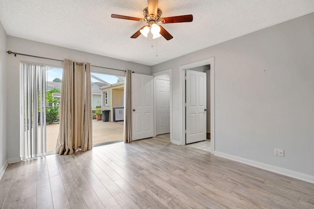 unfurnished room with light wood-type flooring, ceiling fan, a textured ceiling, and baseboards