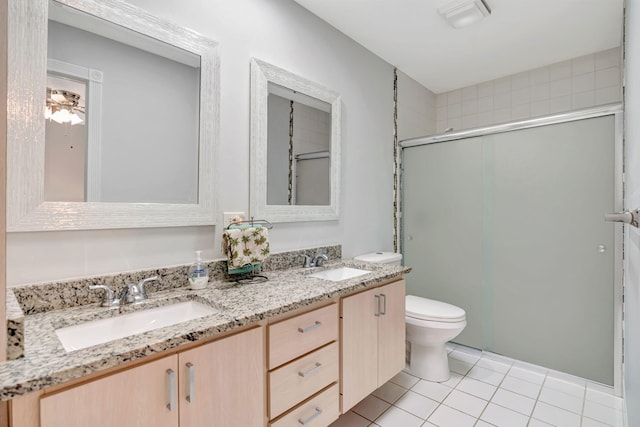 bathroom with toilet, double vanity, a sink, and tile patterned floors